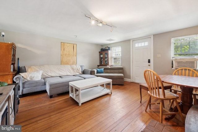 living room with cooling unit, rail lighting, visible vents, light wood-type flooring, and baseboards