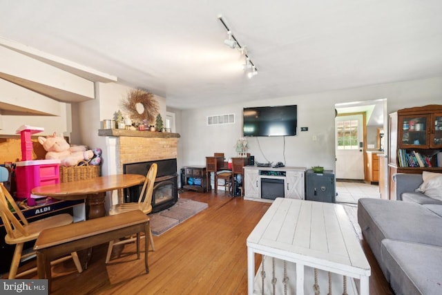 living area featuring light wood-type flooring, visible vents, and track lighting