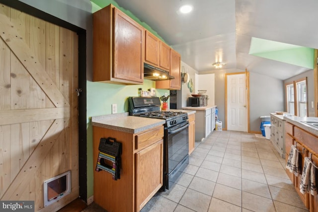 kitchen with black gas range, visible vents, vaulted ceiling, light countertops, and under cabinet range hood