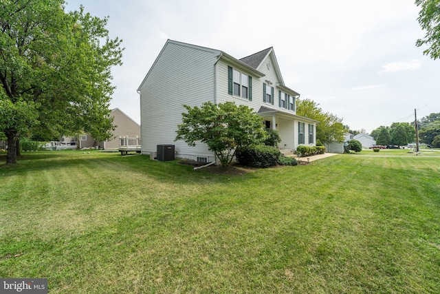 view of side of home featuring cooling unit and a lawn