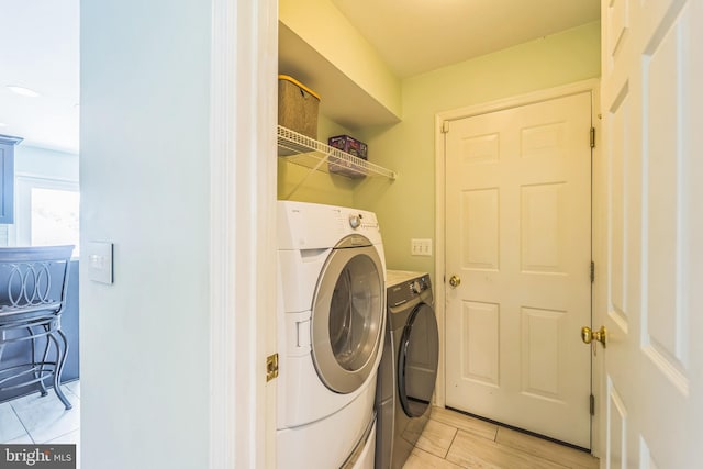 clothes washing area with washing machine and dryer and light tile patterned floors