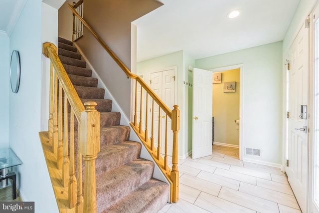 stairway with ornamental molding and tile patterned floors