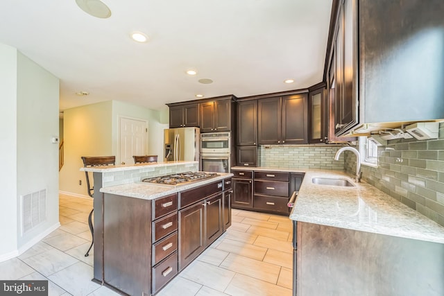 kitchen featuring a kitchen island, a breakfast bar area, appliances with stainless steel finishes, sink, and decorative backsplash