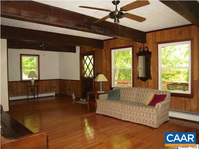 living room with ceiling fan, beam ceiling, hardwood / wood-style flooring, and a baseboard heating unit