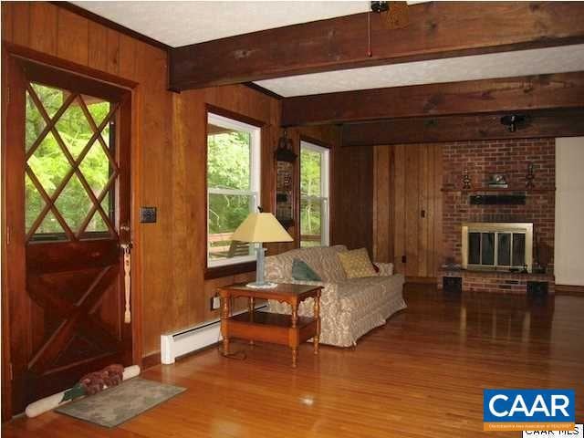 interior space with brick wall, a baseboard radiator, hardwood / wood-style floors, and a brick fireplace