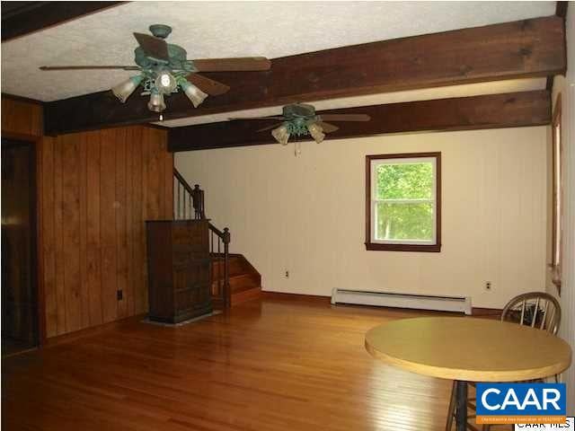 interior space with ceiling fan, a baseboard heating unit, and wood-type flooring