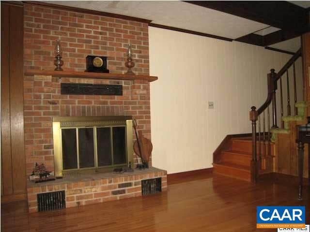 living room with wood-type flooring, brick wall, and a fireplace