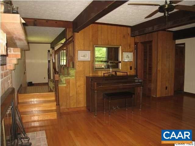 kitchen with ceiling fan, beam ceiling, wood walls, and hardwood / wood-style floors