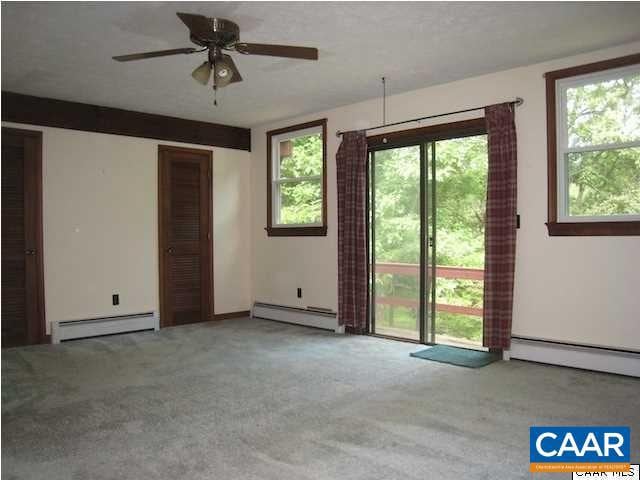 carpeted spare room with ceiling fan and baseboard heating