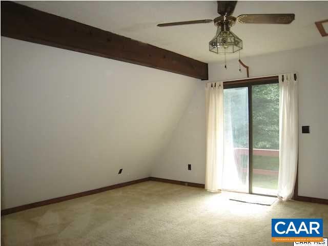 empty room with ceiling fan, vaulted ceiling with beams, and light carpet