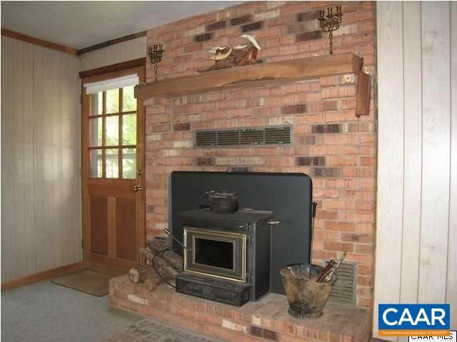 details featuring carpet floors, crown molding, and a wood stove