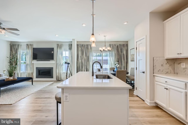 kitchen featuring decorative backsplash, light wood-style flooring, open floor plan, and a sink