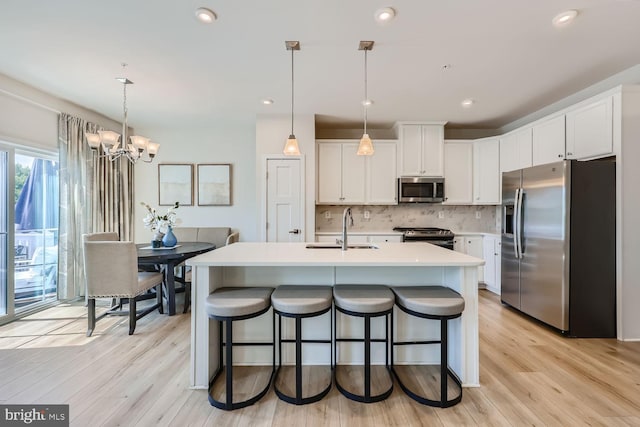 kitchen featuring tasteful backsplash, light wood-style flooring, appliances with stainless steel finishes, and a sink