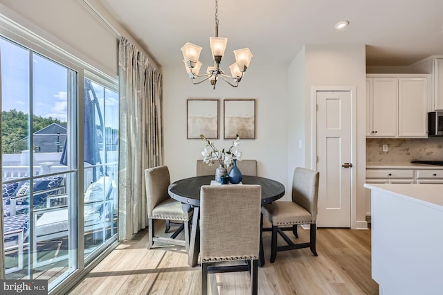 dining space with light wood-style floors and a notable chandelier