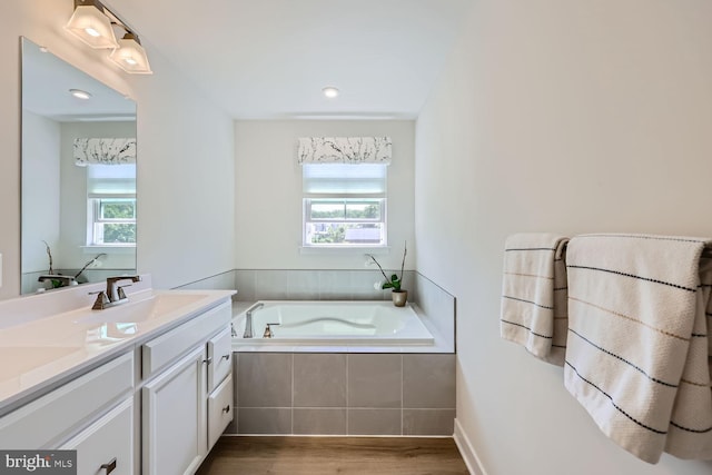 full bathroom with a bath, a wealth of natural light, wood finished floors, and double vanity