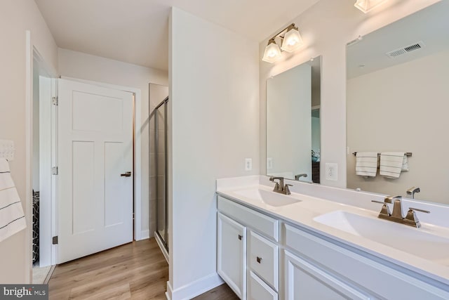 bathroom featuring visible vents, a sink, a shower stall, and double vanity