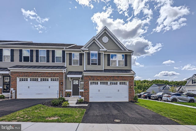 townhome / multi-family property featuring brick siding, an attached garage, a standing seam roof, and aphalt driveway