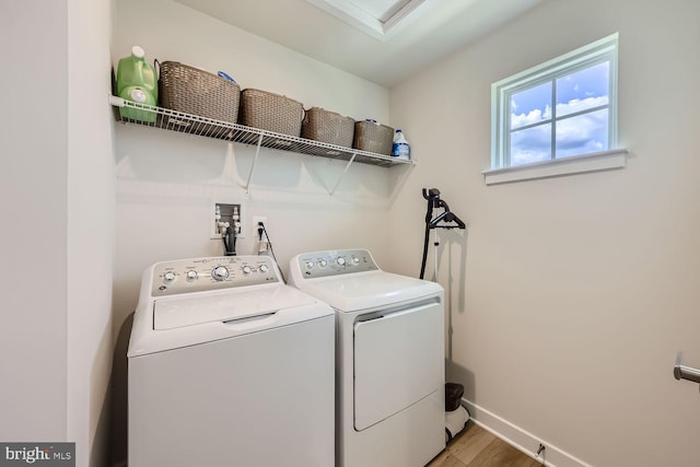 clothes washing area featuring separate washer and dryer, baseboards, light wood-style floors, and laundry area
