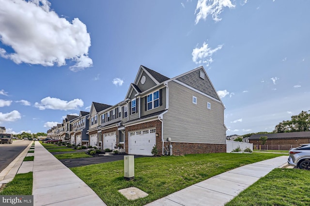 exterior space featuring an attached garage, fence, a front yard, brick siding, and a residential view
