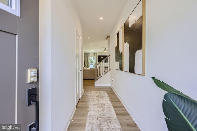 hallway featuring stairway, baseboards, light wood finished floors, and recessed lighting