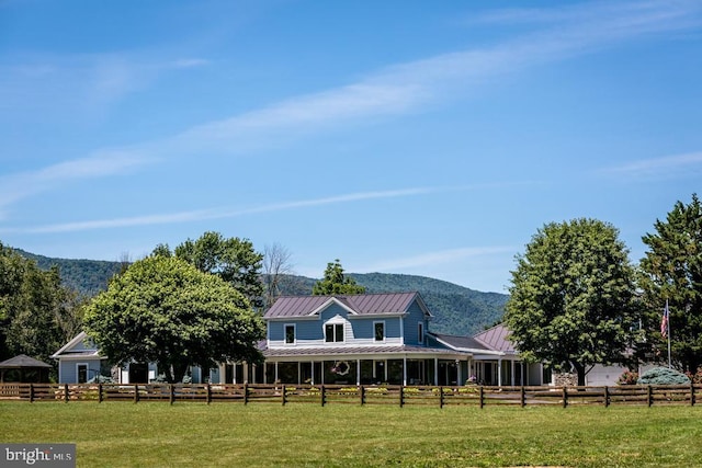 exterior space featuring metal roof, a standing seam roof, a front yard, and fence