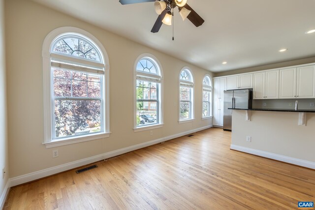 interior space with ceiling fan, vaulted ceiling, and light wood-type flooring