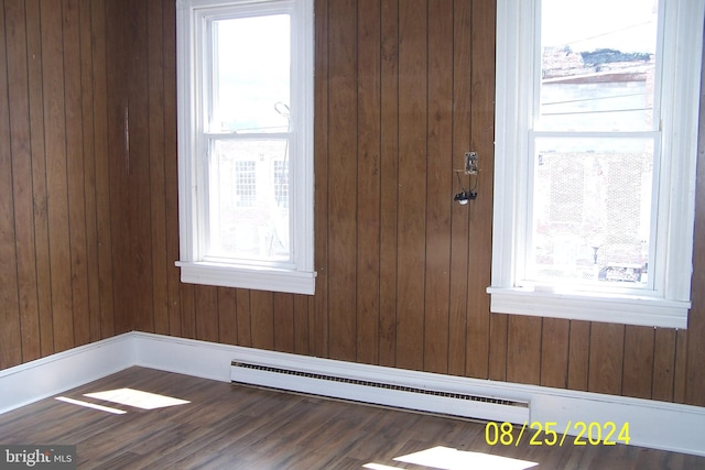 interior space featuring wood walls, a baseboard radiator, a healthy amount of sunlight, and hardwood / wood-style flooring