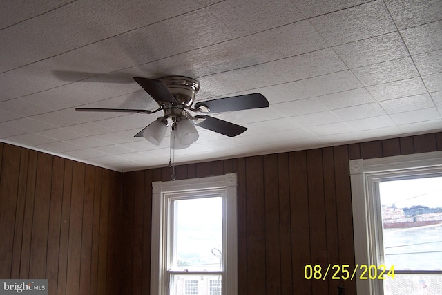 interior details with ceiling fan and wood walls