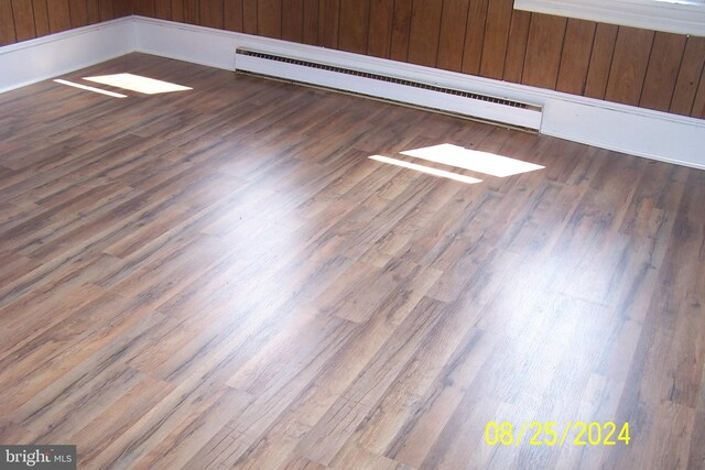 details with hardwood / wood-style flooring, wooden walls, and a baseboard radiator