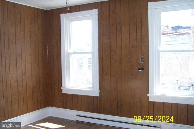 interior space featuring plenty of natural light, baseboard heating, and wood walls