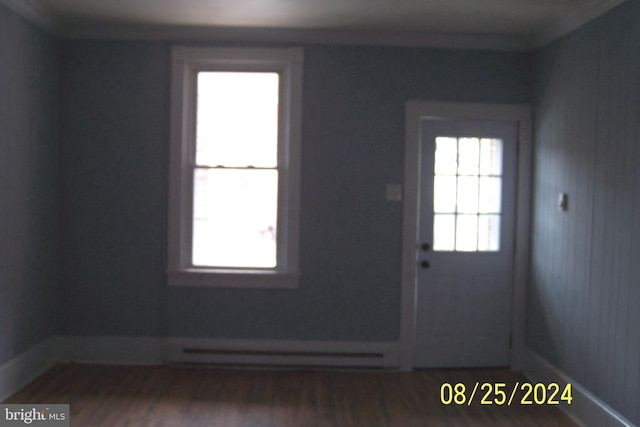 interior space with hardwood / wood-style floors, a baseboard heating unit, and a healthy amount of sunlight