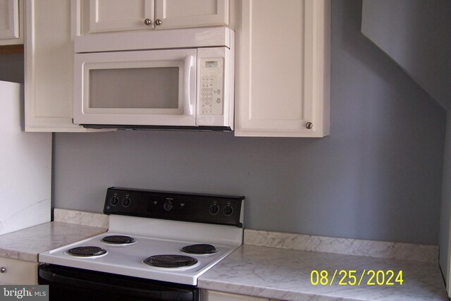 kitchen featuring white cabinetry and white appliances