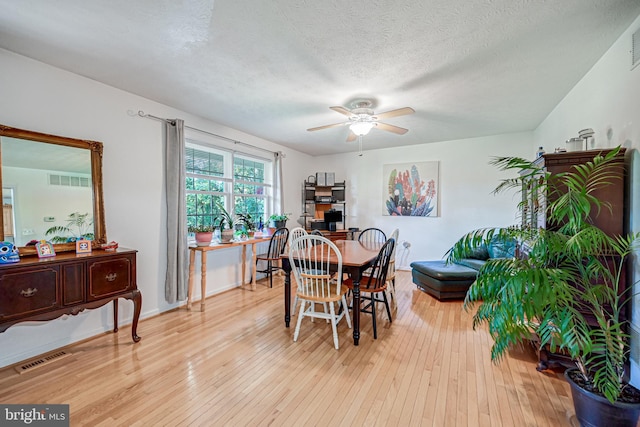 dining area with a textured ceiling, ceiling fan, and light wood-type flooring