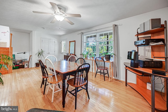 dining space featuring light wood-type flooring, a textured ceiling, and ceiling fan