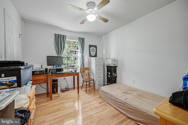 home office with a textured ceiling, ceiling fan, and light wood-type flooring