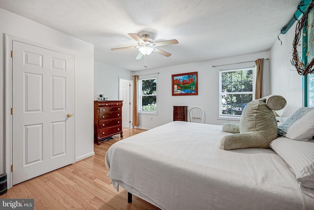 bedroom with ceiling fan, a textured ceiling, and light hardwood / wood-style flooring