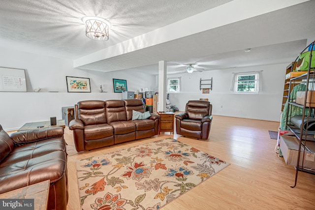 living room with a textured ceiling, light hardwood / wood-style flooring, and ceiling fan