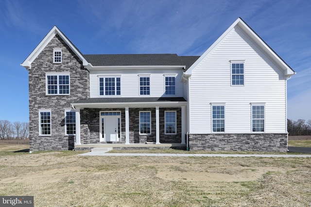 view of front of house with covered porch, stone siding, and roof with shingles