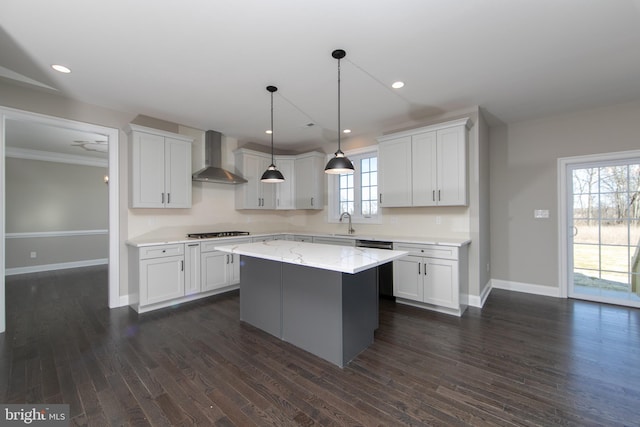 kitchen with a kitchen island, wall chimney range hood, dark hardwood / wood-style flooring, and a healthy amount of sunlight