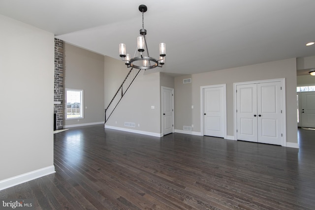 interior space with an inviting chandelier, dark hardwood / wood-style floors, and brick wall