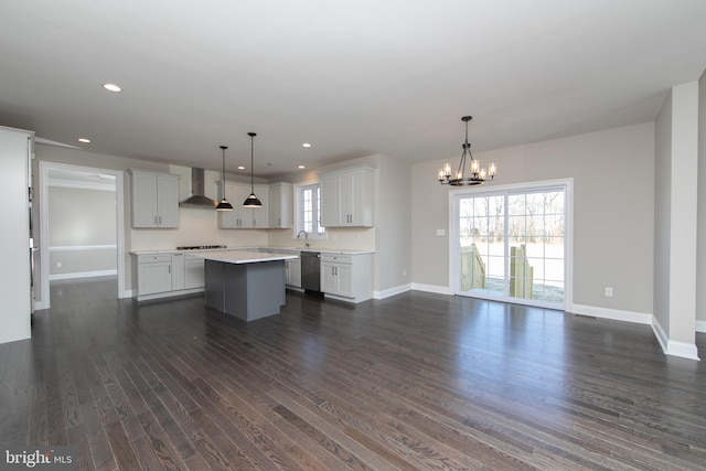 kitchen with white cabinetry, wall chimney range hood, dark hardwood / wood-style flooring, a kitchen island, and hanging light fixtures