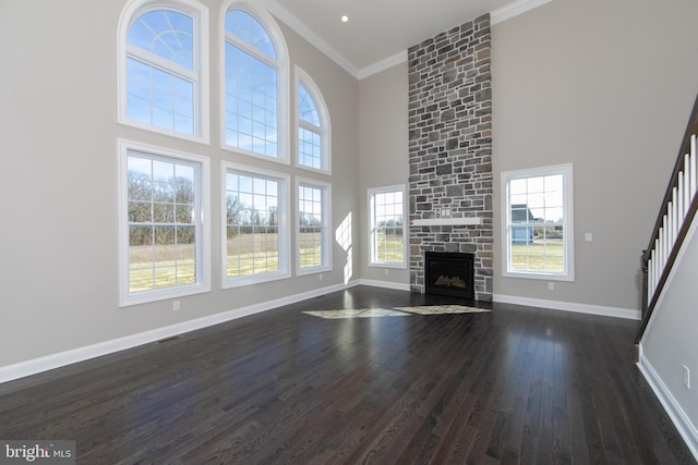 unfurnished living room with dark hardwood / wood-style flooring, a wealth of natural light, and a stone fireplace