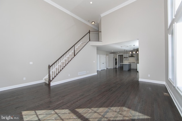 unfurnished living room featuring hardwood / wood-style floors, crown molding, and a high ceiling