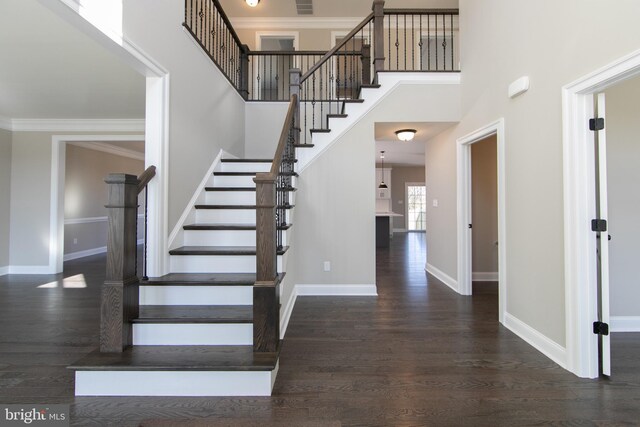 stairs featuring crown molding, hardwood / wood-style floors, and a towering ceiling