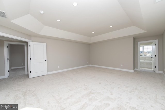 carpeted spare room with a tray ceiling