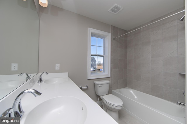 full bathroom featuring tile patterned floors, tiled shower / bath, vanity, and toilet