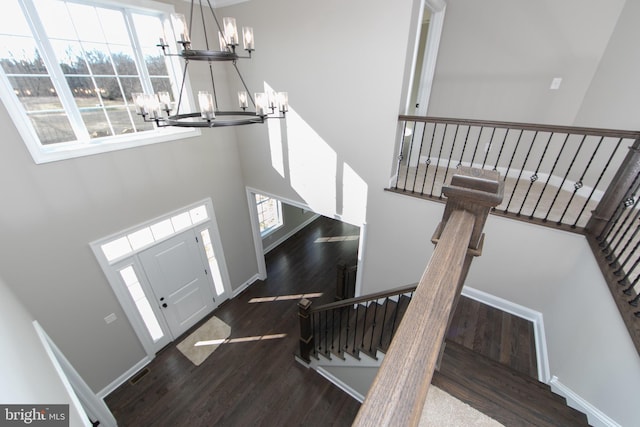 foyer entrance featuring a high ceiling, dark wood-type flooring, and a notable chandelier