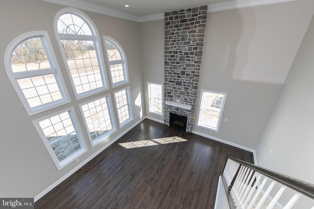 unfurnished living room with a fireplace, plenty of natural light, crown molding, and dark hardwood / wood-style flooring