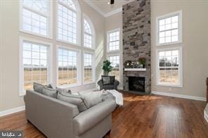 living room with a high ceiling, hardwood / wood-style flooring, a stone fireplace, and brick wall