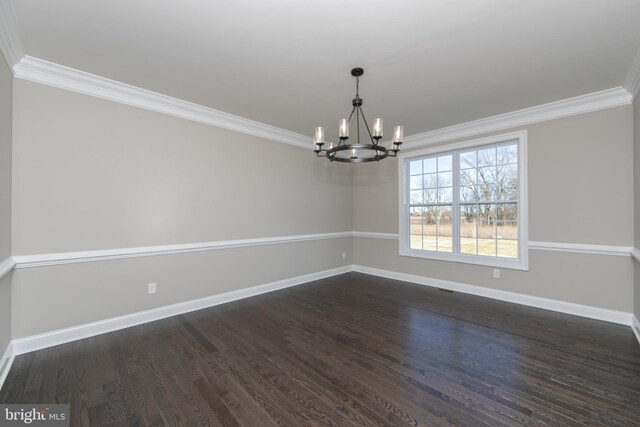 empty room featuring ornamental molding, dark hardwood / wood-style flooring, and a chandelier